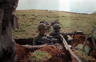 Members of Company C, 1ST Battalion, 21st Infantry Division, equipped with Multiple Intergrated Laser Engagement System (MILES) gear, wait for an attack by opposing forces during the training Exercise OPPORTUNE JOURNEY 4-83. The soldier on the left has an AN/PVS-2 Starlight scope mounted on his M-16 rifle. (SUBSTANDARD)