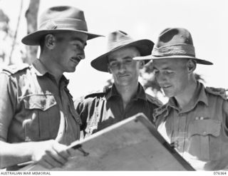 LAE, NEW GUINEA. 1944-10-03. WX5 BRIGADIER R.L. SANDOVER, COMMANDING OFFICER (3), NX70799 MAJOR A.G. LOWNDES, BRIGADE MAJOR (1) AND VX36070 LIEUTENANT R.A. NASH (2) CHECKING OVER A MAP AT THE ..