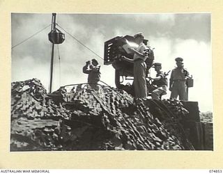 PORT MORESBY, PAPUA. 1944-07-28. RAN PERSONNEL MANNING A 24" SIGNAL PROJECTOR AT THE RAN PORT WAR SIGNAL STATION. IDENTIFIED PERSONNEL ARE:- LIEUTENANT R.J. EDDINGTON, ROYAL AUSTRALIAN NAVY ..