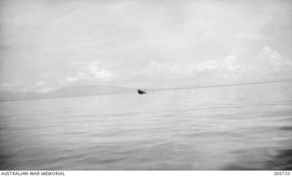 Off Porlock Harbour, New Guinea. After being hit by bombs in an attack by Japanese aircraft off Cape Nelson, the Dutch merchant vessel 'sJacob settles by the bow. Survivors can be seen swimming in ..