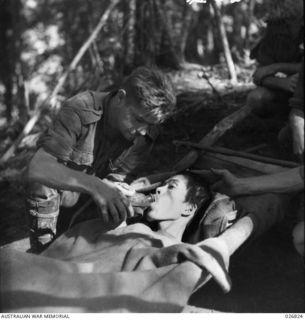 PAPUA, NEW GUINEA. 1942-10. JAPANESE PRISONER CAPTURED NEAR NAURO. HE HAD BEEN OVERWORKED AND WAS NEARLY STARVING WHEN TAKEN PRISONER. HE IS SEEN BEING CARED FOR BY AUSTRALIAN STRETCHER BEARERS