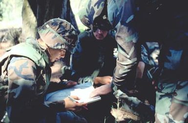 Another Marine helps LCPL Cruz Herrera of Co. A, 1ST Bn., 4th Marines use an aiming circle to calculate firing data for his M-224 60mm mortar. His battalion is participating in Exercise RimPac '88