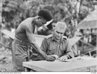 DUMPU AREA, NEW GUINEA. 1944-04-16. NGX308 LIEUTENANT J.L. LEAHY, AUSTRALIAN NEW GUINEA ADMINISTRATIVE UNIT, A MEMBER OF A FAMOUS GOLD MINING FAMILY IN NEW GUINEA, SHOWS ABANUNG, WHERE TO SIGN HIS ..