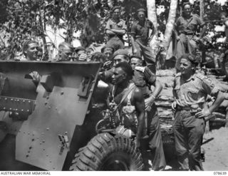 BOUGAINVILLE ISLAND. 1945-01-25. NGN18 CORPORAL KARI SEATED IN THE GUNLAYERS SEAT OF A 25 POUNDER OF "E" TROOP, NO.6 BATTERY, 2ND FIELD REGIMENT AS QX14582 LIEUTENANT J. MARTIN, "A" COMPANY, 1ST ..