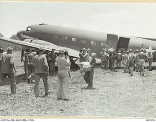 UNITED STATES TROOPS OF THE 32ND UNITED STATES DIVISION UNLOADING THE "SWAMP RAT", A DOUGLAS C47 AIRCRAFT, AFTER IT HAD BECOME BOGGED AT THE END OF THE NEW AIRSTRIP. THIS AIRCRAFT WAS THE FIRST ..