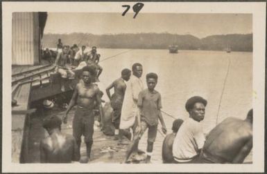 Young men fishing from the pier, Rabaul, New Britain Island, Papua New Guinea, probably 1916