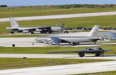 A US Air Force (USAF) B-2 Spirit stealth bomber taxis onto the flightline at Anderson Air Force Base (AFB), Guam (GU), in support of exercise Coronet Bugle 49. The B-2 is deployed to Anderson from Whiteman AFB, Missouri (MO). Close by are B-52 Stratofortress bomber aircraft