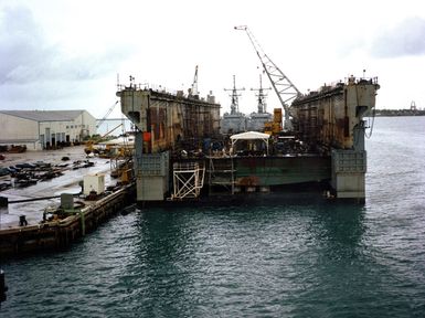 A floating dry dock is moored at the harbor at the US Naval Ship Repair Facility