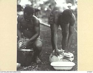 MALAMAL, NEW GUINEA. 1944-07-13. NATIVE COOKS MEASURING OUT RICE FOR THE EVENING MEAL AT THE AUSTRALIAN NEW GUINEA ADMINISTRATIVE UNIT NATIVE LABOUR COMPOUND