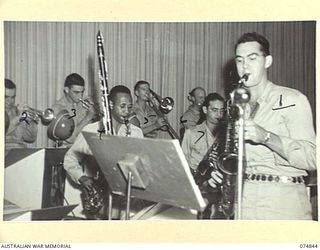 LAE, NEW GUINEA. 1944-07-24. A MEMBER OF THE AMERICAN SPECIAL SERVICES BAND PLAYS A SAXOPHONE SOLO DURING A CONCERT FOR THE TROOPS BY THE JACK BENNY SHOW