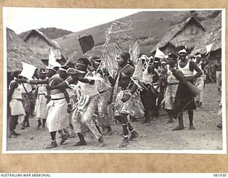 KILA KILA, PAPUA, NEW GUINEA. 1943-12-25. KEREMA BOYS EXECUTING A DANCE AT THE AUSTRALIAN AND NEW GUINEA ADMINISTRATION UNIT NATIVE LABOUR CAMP. THE DANCERS WEAR LONG TRAILS OF GRASS AND FLOWERS, ..