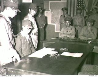 THE SOLOMON ISLANDS, TOROKINA, BOUGAINVILLE ISLAND, 1945-09-08. LIEUTENANT GENERAL MASATANE KANDA, COMMANDER XVII JAPANESE ARMY, WITH HIS TWO INTERPRETERS, READ DETAILS OF THE ACTION REQUIRED BY ..