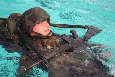 Marine CPL. Melanie Burkett makes her way the length of the pool to demonstrate her combat water survivability with full pack and rifle