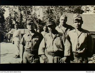 Torokina, Bougainville, New Guinea. 1945-09. Three Japanese prisoners of war and their unidentified Australian guard at the 2/1st Australian General Hospital (2/1AGH). Note the walking patient ..