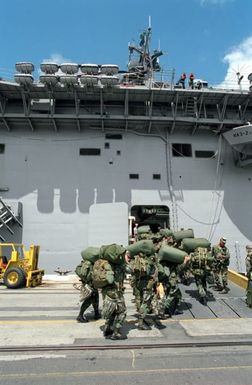 Troops of the 25th Infantry Division assemble on the pier as they prepare to board the amphibious assault ship USS BELLEAU WOOD (LHA-3) for transport to the island of Kauai as part of Task Force Garden Isle, a joint military disaster relief effort being conducted in the aftermath of Hurricane Iniki
