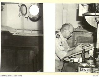 HOMBOLT BAY, NEW GUINEA. 1944-08/09. ENGINEER LIEUTENANT I.L. BARTON, WHOSE HOBBY IS ART, COMPLETING A PAINTING IN HIS CABIN ABOARD THE RAN CORVETTE, GEELONG