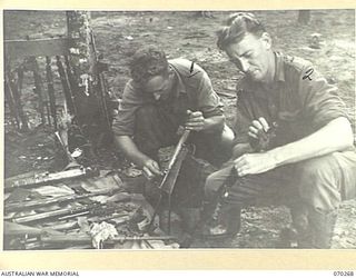 DUMPU, RAMU VALLEY, NEW GUINEA, 1944-02-10. V43884 PRIVATE R. LONG (1) AND V200760 PRIVATE C. BENNETTS (2) OF "B" COMPANY, 57/60TH INFANTRY BATTALION, CLEANING WEAPONS AFTER THE BATTALION'S RETURN ..