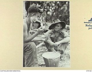 TSIMBA AREA, BOUGAINVILLE ISLAND. 1945-02-21. NX135539 PRIVATE SLATER, 26TH INFANTRY BATTALION (1) ENJOYING THE LUXURY OF A SHAVE WHILE CHATTING WITH HIS FRIEND NX13599 CORPORAL R.S. MCGRATH (2)