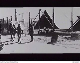 SALAMAUA, NEW GUINEA, 1940-06?. GUARD ROOM FOR THE INTERNMENT CAMP, COMPRISING TENTS ON THE FORMER TENNIS COURTS. MEMBERS OF THE NEW GUINEA VOLUNTEER RIFLES (NGVR), SEEN ON GUARD, WERE CIVILIANS ..