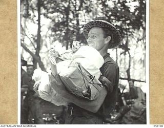 SCARLET BEACH, NEW GUINEA, 1943-10-25. NX21680 PRIVATE C.G. BAILEY OF THE 2/17TH AUSTRALIAN INFANTRY BATTALION COLLECTS HIS ARMFUL OF MAIL
