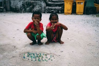 Two children playing marbles, Fakaofo, Tokelau