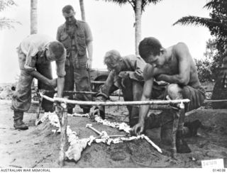 1943-01-08. PAPUA. GIROPI POINT. AUSTRALIANS TEND GRAVES OF COMRADES WHO FELL IN THE FINAL ASSAULT ON BUNA. DECORATIONS ARE OF CORAL FROM NEARBY REEF