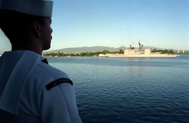 A crew member aboard the battleship USS MISSOURI (BB-63) watches the guided missile cruiser USS CHOSIN (CG-65) as it passes the USS ARIZONA MEMORIAL during an observance commemorating the 50th anniversary of the Japanese attack on Pearl Harbor