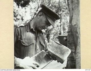 KILIGIA, NEW GUINEA, 1944-03-14. NX100431 MAJOR E. J. CULEY, SENIOR SUPPLY OFFICER, 5TH DIVISION EXAMINING BREAD FOR SIGNS OF COPRA BUG