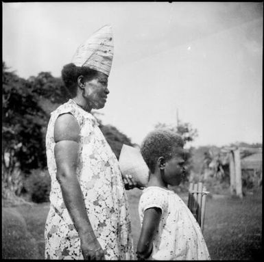 Woman wearing a conical hat and a young girl standing in front of her, New Guinea, ca. 1936 / Sarah Chinnery
