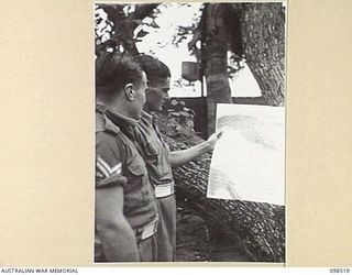 CAPE PUS, NEW GUINEA. 1945-11-03. CORPORAL C. LETCHFIELD (1) AND SERGEANT S.E. BAILEY (2) STUDYING THE DAGUA AREA ON A MAP WHERE THEY FOUGHT AS MEMBERS OF THE 2/2 INFANTRY BATTALION PLATOON ..