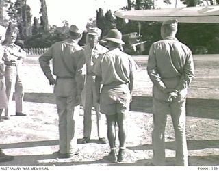 THE SOLOMON ISLANDS, 1945. AMERICAN MAJOR GENERAL R.J. MITCHELL CHATS WITH OTHER OFFICERS PRIOR TO HIS DEPARTURE FROM BOUGAINVILLE ISLAND. THE PORT WING TIP OF AN US C47 APPEARS IN THE UPPER RIGHT ..