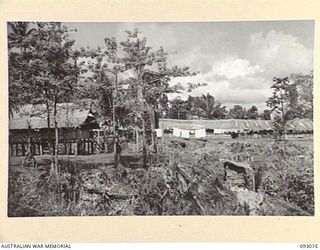 MOROKAIMORO, BOUGAINVILLE, 1945-06-06. HEADQUARTERS, 2/8 COMMANDO SQUADRON, SHOWING HOSPITAL IN RIGHT BACKGROUND, CAPT C.A. HOLMES, AUSTRALIAN ARMY MEDICAL CORPS, IS IN CHARGE OF THE HOSPITAL