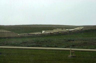 Parts of the wall surrounding the flight line area lay in ruins after super-typhoon Pongsona struck Sunday December 8th at Andersen Air Force Base (AFB), Guam