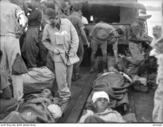 LALUM, BOUGAINVILLE, 1945-06-12. PATIENTS FROM 19 FIELD AMBULANCE MAIN DRESSING STATION WAITING ON A BARGE BEFORE BEING TRANSFERRED TO THE HOSPITAL SHIP STRADBROKE. THE MEN WERE WOUNDED DURING THE ..