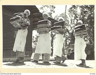 LAE, NEW GUINEA. 1944-03-30. BAKERS AT THE 8TH FIELD BAKING PLATOON CARRYING BREAD WHICH THEY HAVE BAKED. LEFT TO RIGHT: VX144324 PRIVATE (PTE) L. T. HODGSON; VX104647 CORPORAL K. J. MALANEL ..