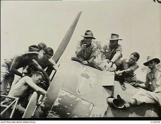 NADZAB, NEW GUINEA. C. 1944-02. GROUND CREW MEMBERS OF NO. 24 (VENGEANCE) SQUADRON RAAF ATTACH A PAINTING (NOSE ART) OF JUNE MCPHERSON, "ADOPTED" TIVOLI GIRL PERFORMER, TO AN AIRCRAFT