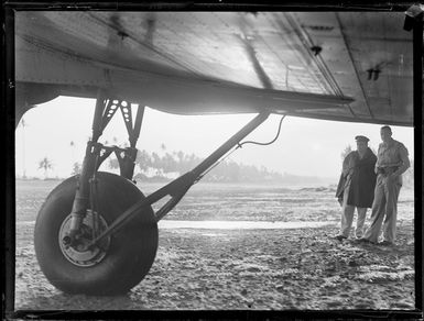 Unidentified military personnel inspect the undercarriage of a transport plane, Faleolo Airport, Western Samoa