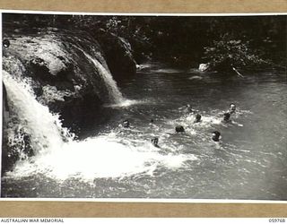 FINSCHHAFEN AREA, NEW GUINEA, 1943-10-25. TROOPS OF THE 9TH AUSTRALIAN DIVISION SWIMMING BELOW THE FALLS ON THE MAPE RIVER NEAR THE TIMBULUM SAW MILL