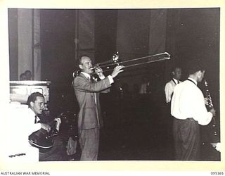 TOROKINA, BOUGAINVILLE, 1945-08-16. SERGEANT F. COUGHLAN, BAND LEADER, 10 DETACHMENT ARMY SHOW, AND A MEMBER OF THE GRACIE FIELDS CONCERT PARTY, ENTERTAINING TROOPS DURING THEIR TOUR OF ..