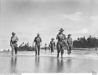 BABIANG, NEW GUINEA. 1944-11-09. TROOPS OF 2/10 COMMANDO SQUADRON WADING ASHORE FROM AN AMPHIBIOUS DUKW STRANDED AT DRINIUMOR RIVER DURING THEIR JOURNEY TO BABIANG. IDENTIFIED PERSONNEL ARE:- ..