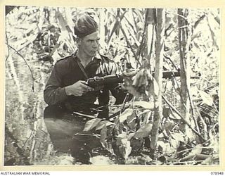 BOUGAINVILLE ISLAND. 1945-01-21. VX140735 PRIVATE R. RATCLIFFE, A MEMBER OF A CONTACT PATROL FROM "D" COMPANY, 42ND INFANTRY BATTALION TAKING COVER DURING A PATROL THROUGH THE SWAMP AREA