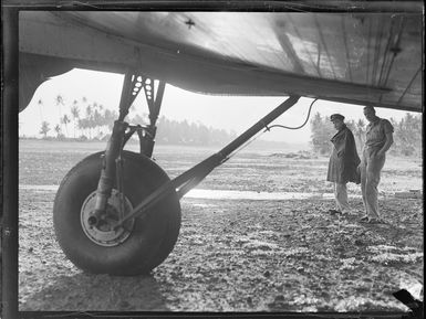 Unidentified military personnel inspect the undercarriage of a transport plane, Faleolo Airport, Western Samoa