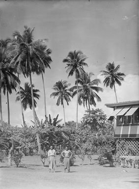 [Portrait of two Pacific Island men in front of building and trees]