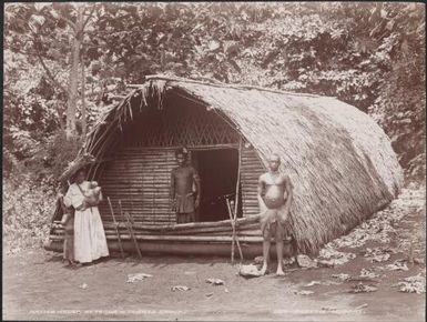 Two men with a woman and two children outside a house at Tegua, Banks Islands, 1906 / J.W. Beattie