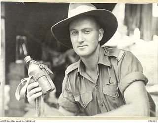 FINSCHHAFEN, NEW GUINEA. 1944-09-20. VX66864 CORPORAL C.F.J. SEYMOUR 8TH INFANTRY BATTALION, DISPLAYING A JAPANESE OFFICER'S WATER BOTTLE. THE BOTTLE IS SMALLER IN SIZE THAN THE ONE ISSUED TO ..