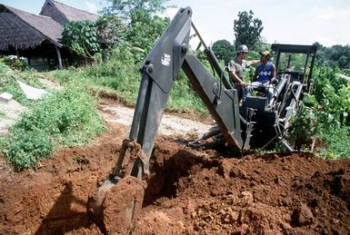 A Seabee from Construction Battalion Unit 3 (CBU-3) gives some pointers to an island resident operating an excavator. Seabees from CBU-3 are working with island residents to make improvements on a school as part of a civic action project