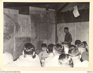 MALMAL VILLAGE, NEW BRITAIN. 1944-12-16. MAJOR E H BURGESS, (1), SPEAKING DURING AN OFFICER'S CONFERENCE HELD IN THE BATTLE ROOM AT HQ 5 DIVISION