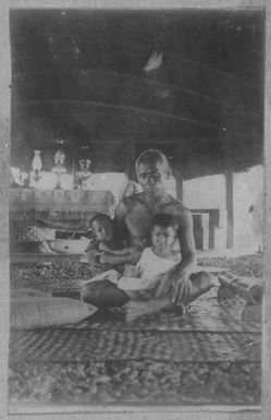 Samoan man and two children in a fale. From the album: Skerman family album