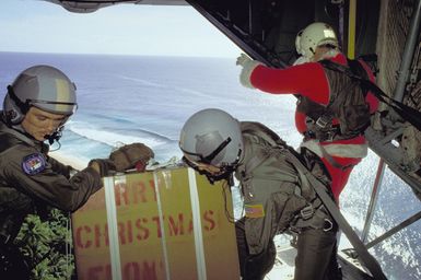 Personnel from the 345th and 21st Tactical Airlift Squadrons prepare to release a package out of the cargo bay of their C-130 Hercules aircraft, as Santa Claus (MGEN Alexander K. Davidson, commander, 22nd Air Force) stands by. Donated Christmas gifts are being parachuted onto local islands