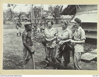 LAE, NEW GUINEA, 1945-05-07. AUSTRALIAN WOMEN'S ARMY SERVICE SIGNAL PERSONNEL WHO HAVE JUST SETTLED INTO THE AUSTRALIAN WOMEN'S ARMY SERVICE BARRACKS IN BUTIBUM ROAD SPEAKING TO ONE OF THE NATIVES ..